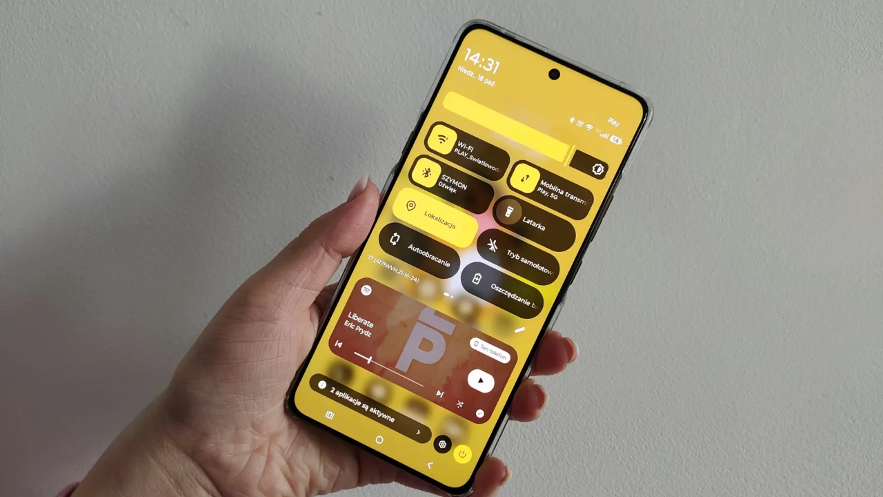 Dłoń trzyma smartfon z otwartym panelem szybkich ustawień Android 17 w języku polskim